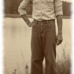 Vintage-Dunkelhäutiger Mann am See, eine Hand an der Hüfte, barfuß.