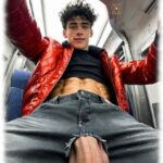 Twink in Metro sitzend, Loch in Hose mit heraushängenden Glückskugeln, Lustpendel liegt darüber.