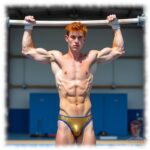 Rothaariger Twink in Sporthalle am Reck, goldfarbene Shorts mit lustvollem Hügel.