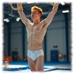 Ginger Men in Sporthalle an den Ringen, weiße Shorts mit dezenter Linie im Stoffverlauf.