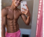 Durchtrainierter Blondschopf mit pinkfarbenen Shorts hält Smartphone in der Hand. Durchtrainierter Blondschopf mit pinkfarbenen Shorts hält Smartphone in der Hand.