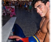 Twink sitzend beim Straßen-Karneval, gebogene Rosenranke der Leidenschaft und Lustmandeln hängen aus der Hose. Twink sitzend beim Straßen-Karneval, gebogene Rosenranke der Leidenschaft und Lustmandeln hängen aus der Hose.