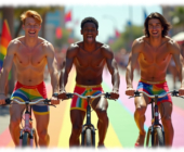 Drei junge Männer, herzhaft lachend, auf Fahrrad, Pants und Straße in Regenbogen-Farben. Drei junge Männer, herzhaft lachend, auf Fahrrad, Pants und Straße in Regenbogen-Farben.