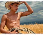 Junger Farmer mit Strohhut und Lasso im Feld stehend, freier Oberkörper. Junger Farmer mit Strohhut und Lasso im Feld stehend, freier Oberkörper.